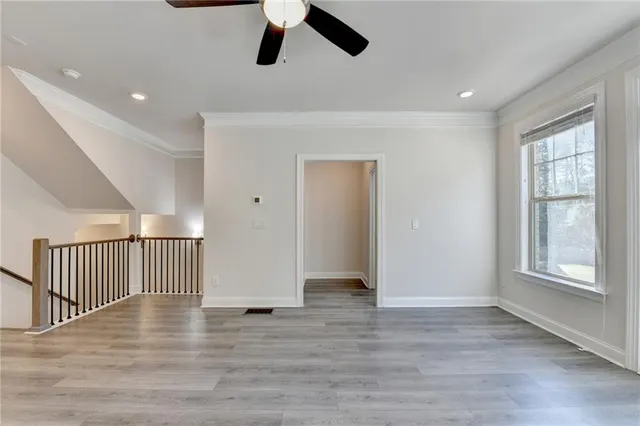 a view of an empty room with wooden floor and window