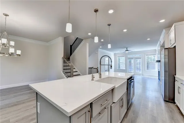 a large kitchen with sink a refrigerator and chairs