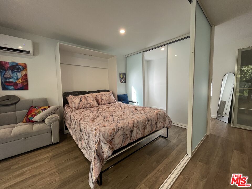 a bedroom with a bed couch and a wooden floor