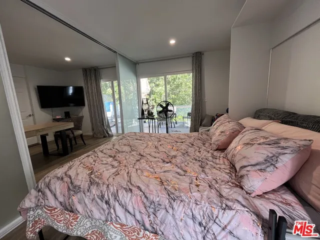 a bedroom with a bed and a flat tv screen on the dresser