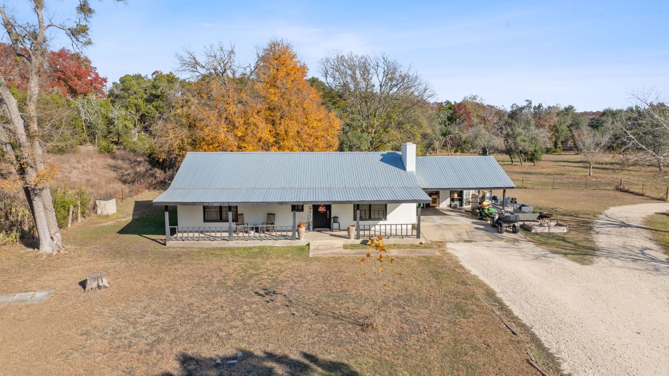 801 Needham Road Dripping Springs, TX 78620 - Photo 35 of 36 View of front of house featuring a porch, driveway, a metal roof, an attached carport, and a chimney
