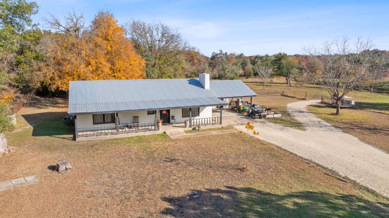 801 Needham Road Dripping Springs, TX 78620 - Photo 6 of 36 View of front of house with covered porch, a metal roof, a front lawn, gravel driveway, and a carport