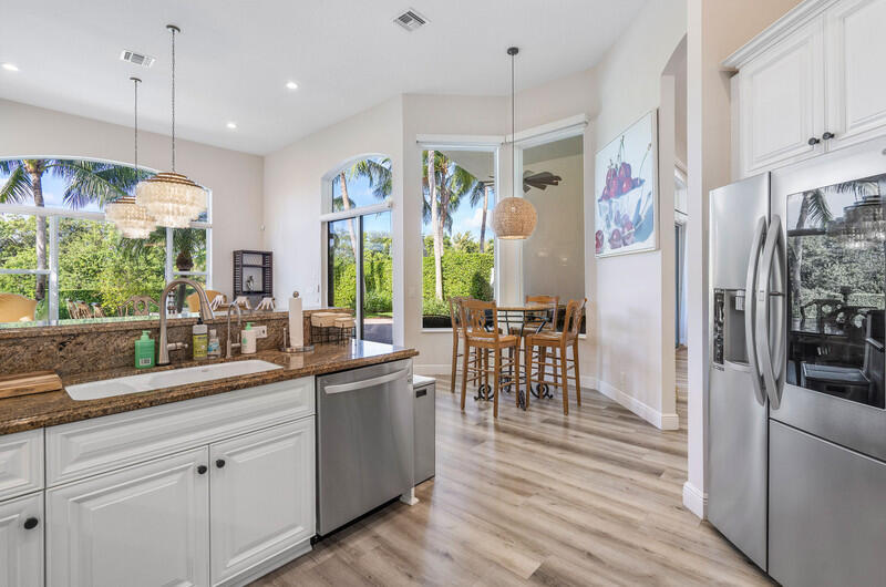 14364 Stroller Way Wellington, FL 33414 - Photo 4 of 47 a kitchen with stainless steel appliances granite countertop a refrigerator a sink dishwasher a dining table and chairs with wooden floor