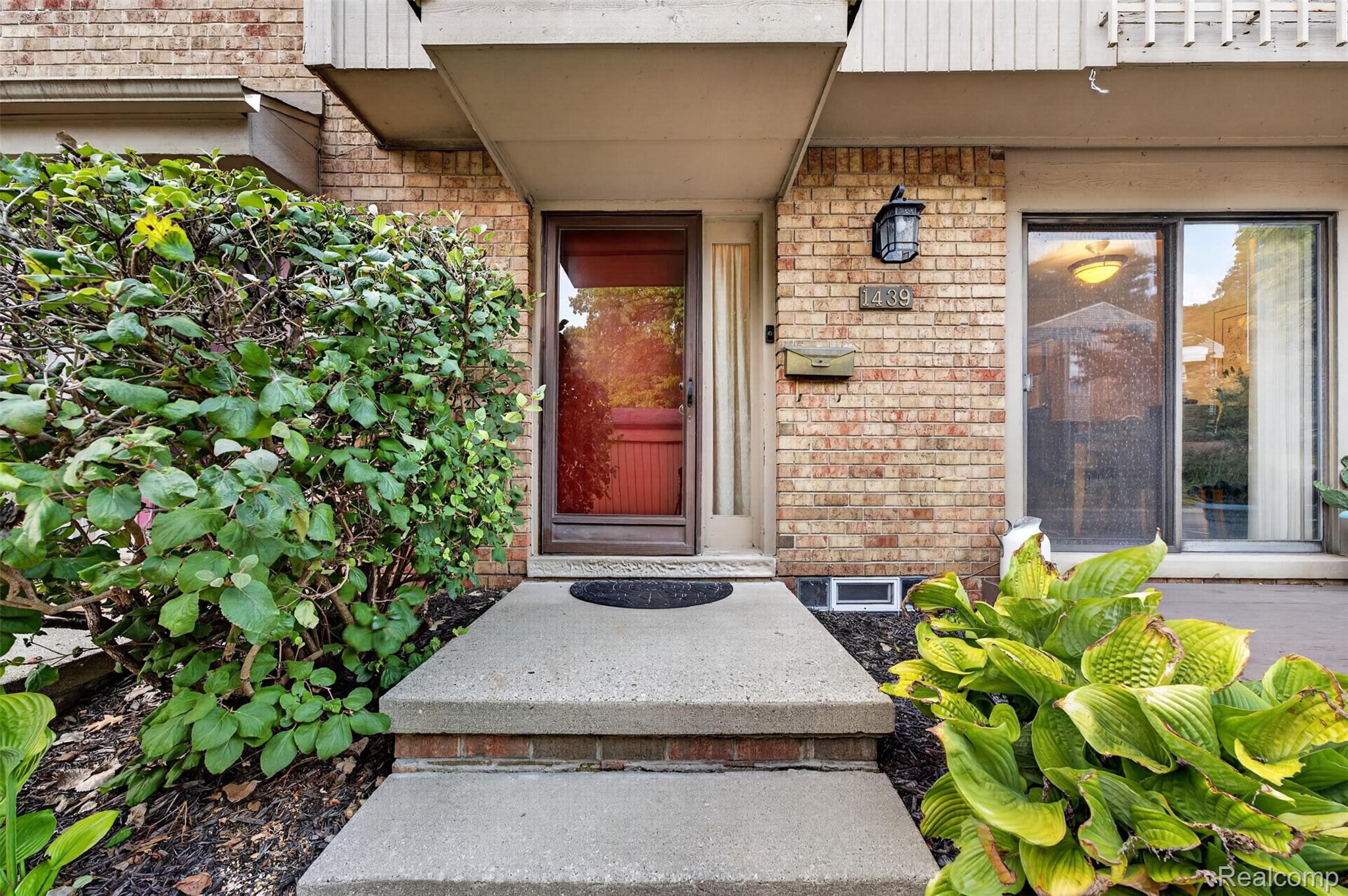 1439 Oakbrook E Drive Rochester, MI 48307 - Photo 3 of 68 Brick exterior with an overhead awning and a concrete entry path