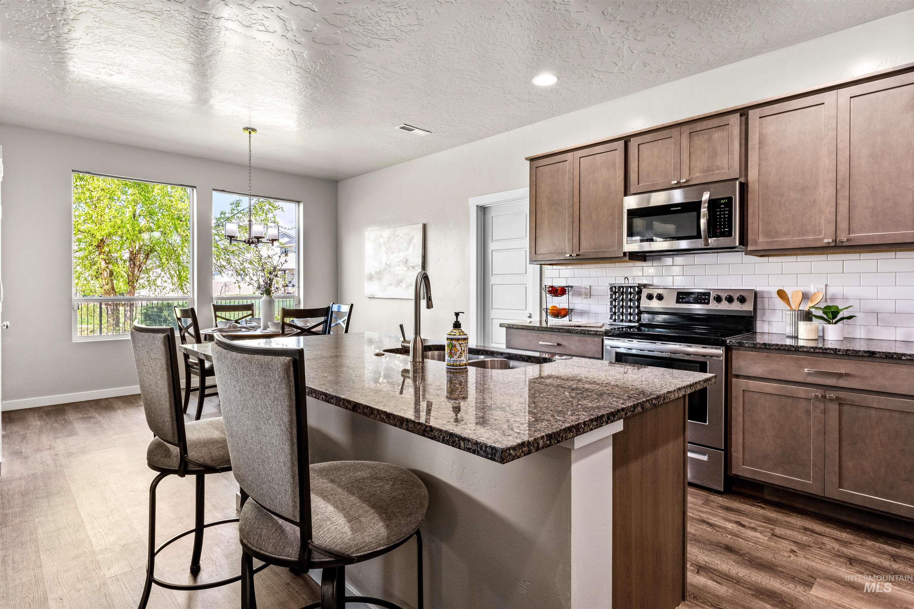 10890 West Sharpthorn Street Boise, ID 83709 - Photo 11 of 50 Kitchen featuring a large island with a stone countertop, an undermount sink, and a gooseneck faucet