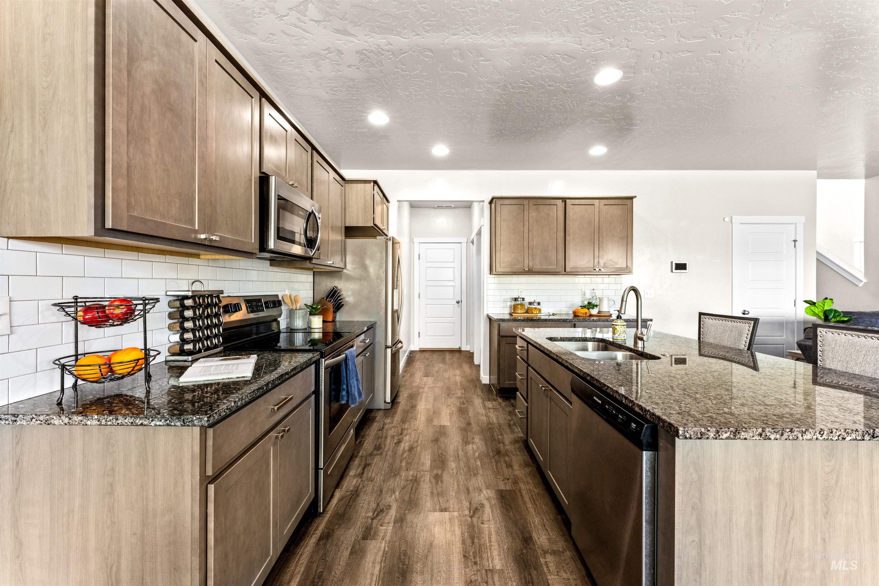 10890 West Sharpthorn Street Boise, ID 83709 - Photo 13 of 50 Kitchen featuring granite countertops, stainless steel appliances, wood-finish flooring, subway tile backsplash, and recessed lighting
