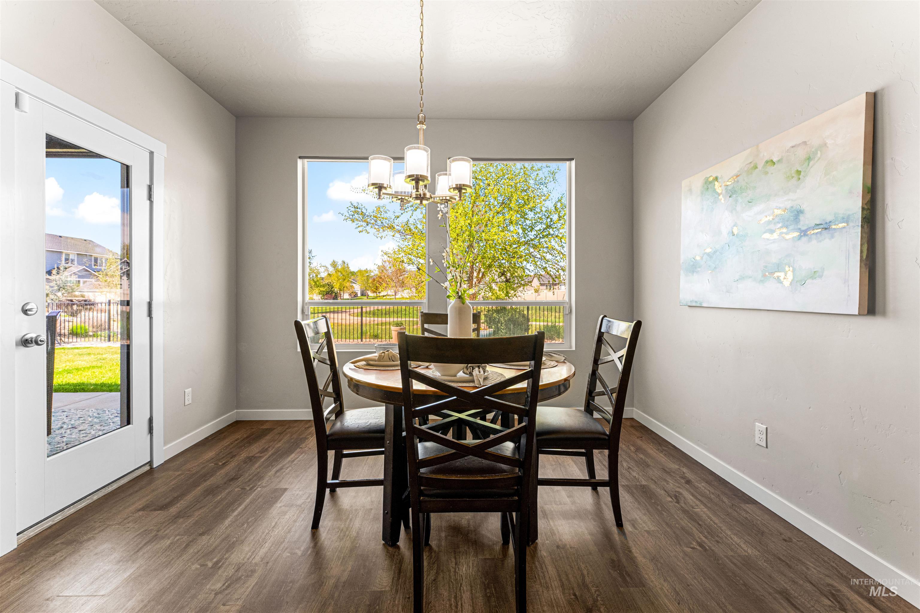 10890 West Sharpthorn Street Boise, ID 83709 - Photo 18 of 50 Dining area featuring wood-finish flooring, a contemporary chandelier, and a large window overlooking green space