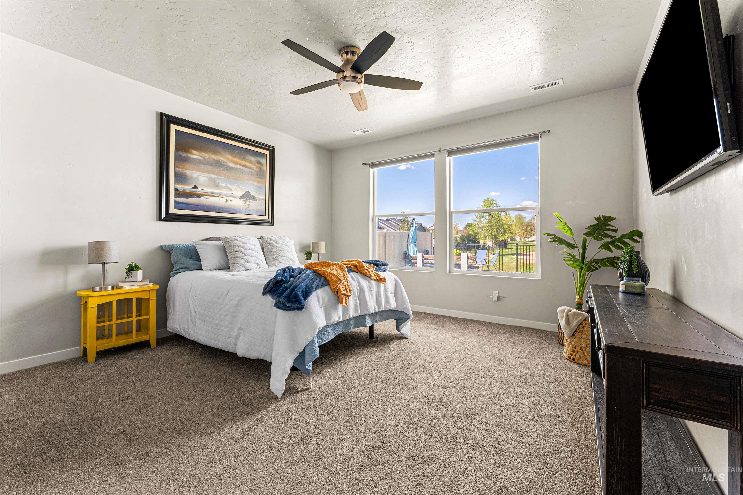 10890 West Sharpthorn Street Boise, ID 83709 - Photo 21 of 50 Carpeted bedroom with a ceiling fan, dual large windows, and a wall-mounted flat-screen television