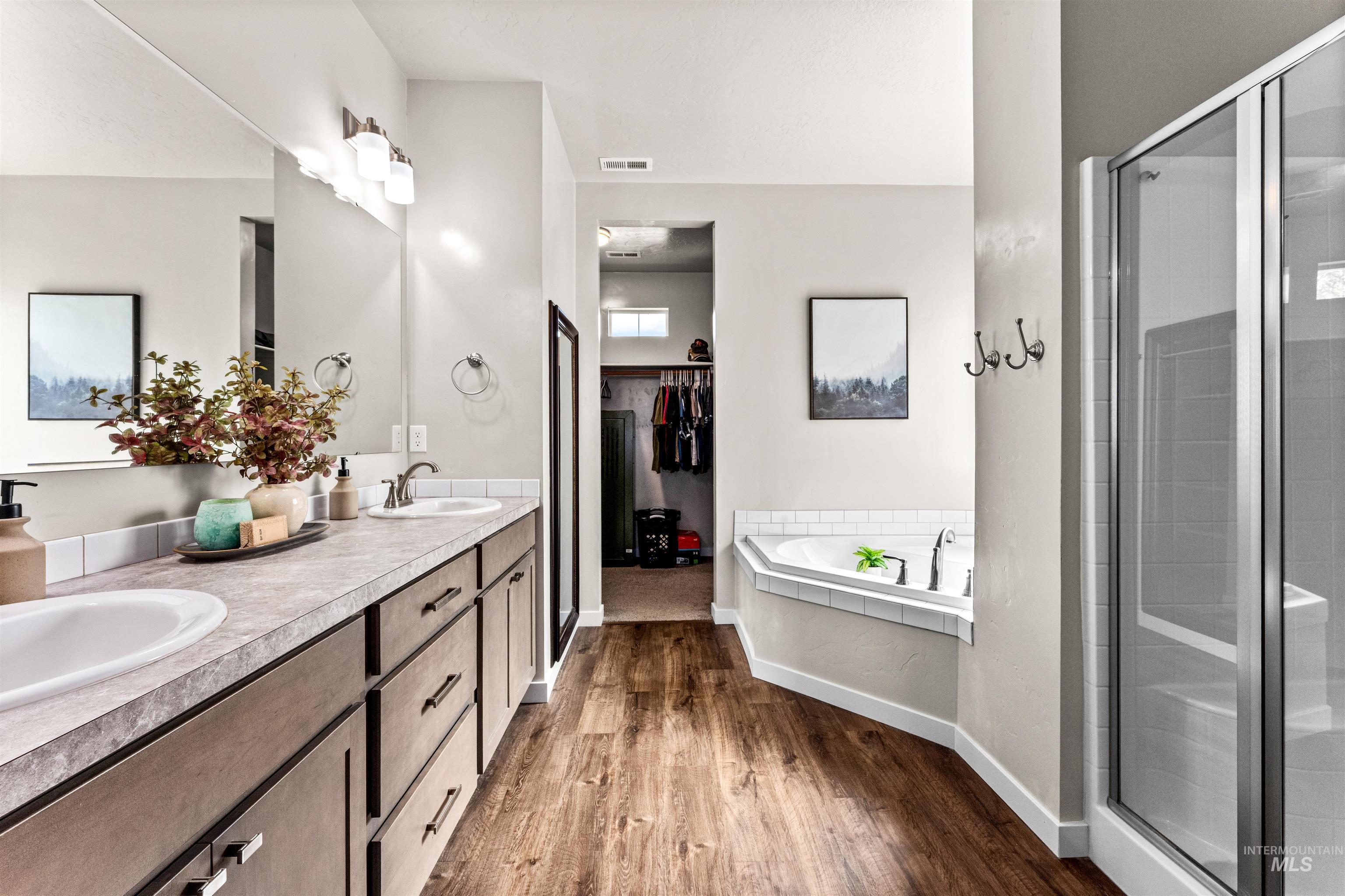 10890 West Sharpthorn Street Boise, ID 83709 - Photo 25 of 50 Spacious bathroom featuring wood-finish flooring, a double vanity with undermount sinks, a corner soaking tub with tile surround, and a glass-enclosed shower