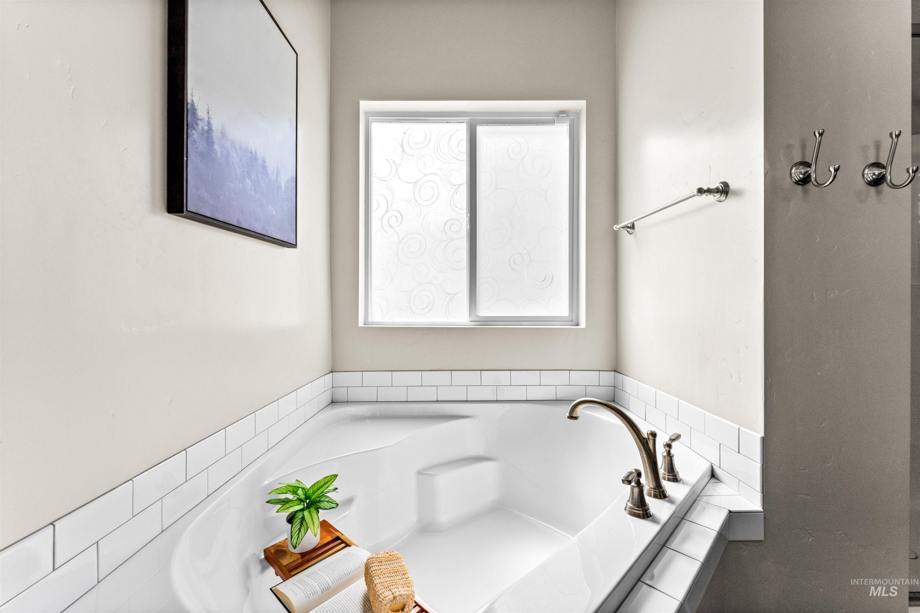 10890 West Sharpthorn Street Boise, ID 83709 - Photo 26 of 50 Soaking tub with a bronze-finish deck-mounted faucet and white subway tile surround