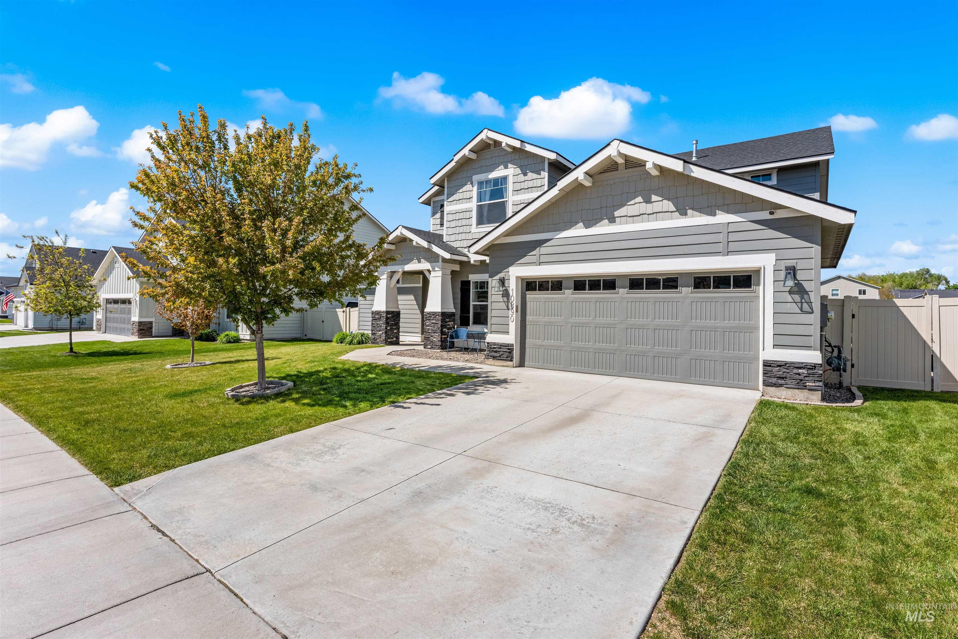 10890 West Sharpthorn Street Boise, ID 83709 - Photo 3 of 50 Contemporary gray siding exterior with stone accents, a two-car garage, concrete driveway, and a manicured lawn