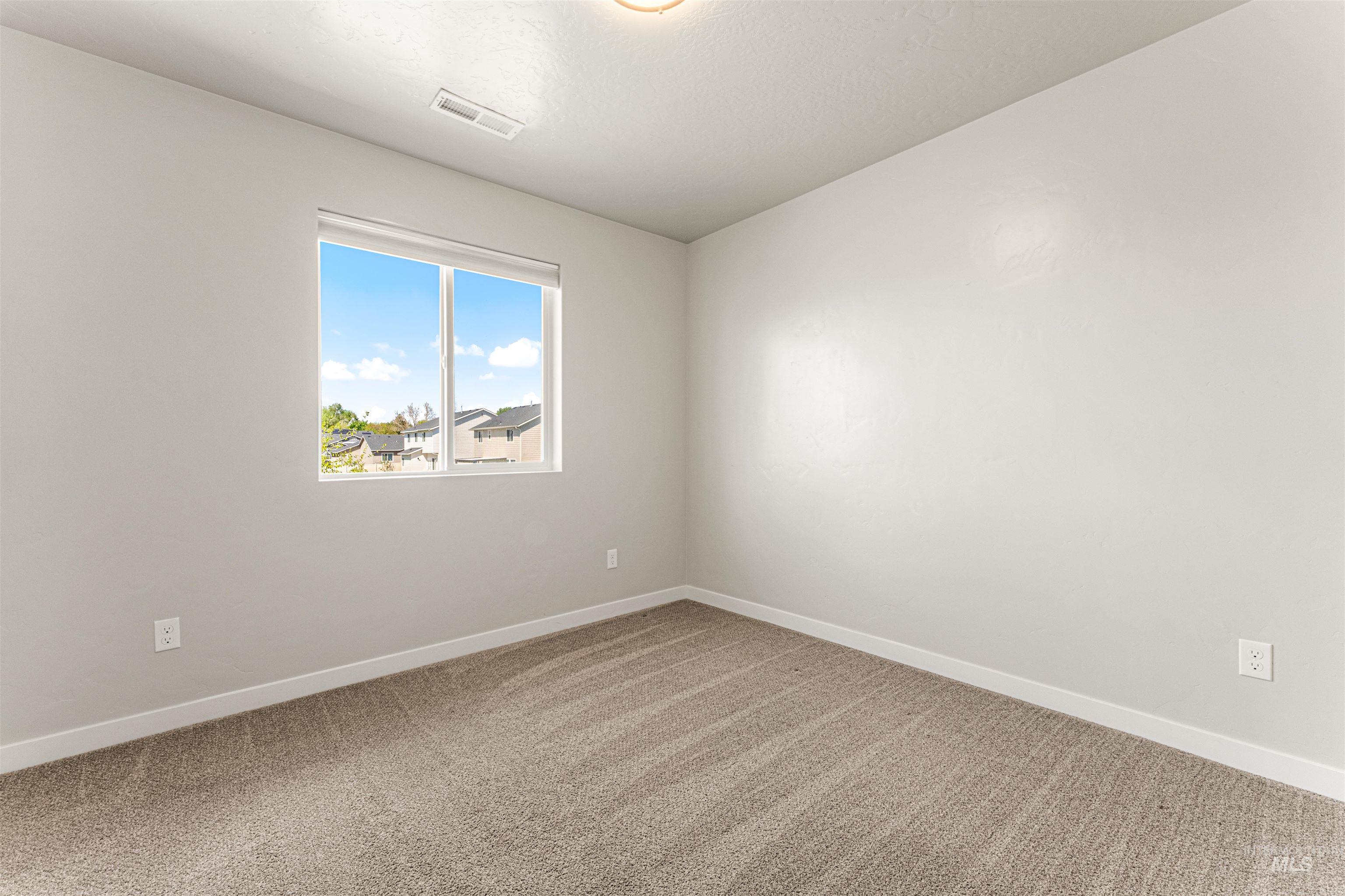10890 West Sharpthorn Street Boise, ID 83709 - Photo 39 of 50 Bright interior room featuring a large window, neutral wall paint, textured carpet flooring, white baseboards, and a ceiling light fixture
