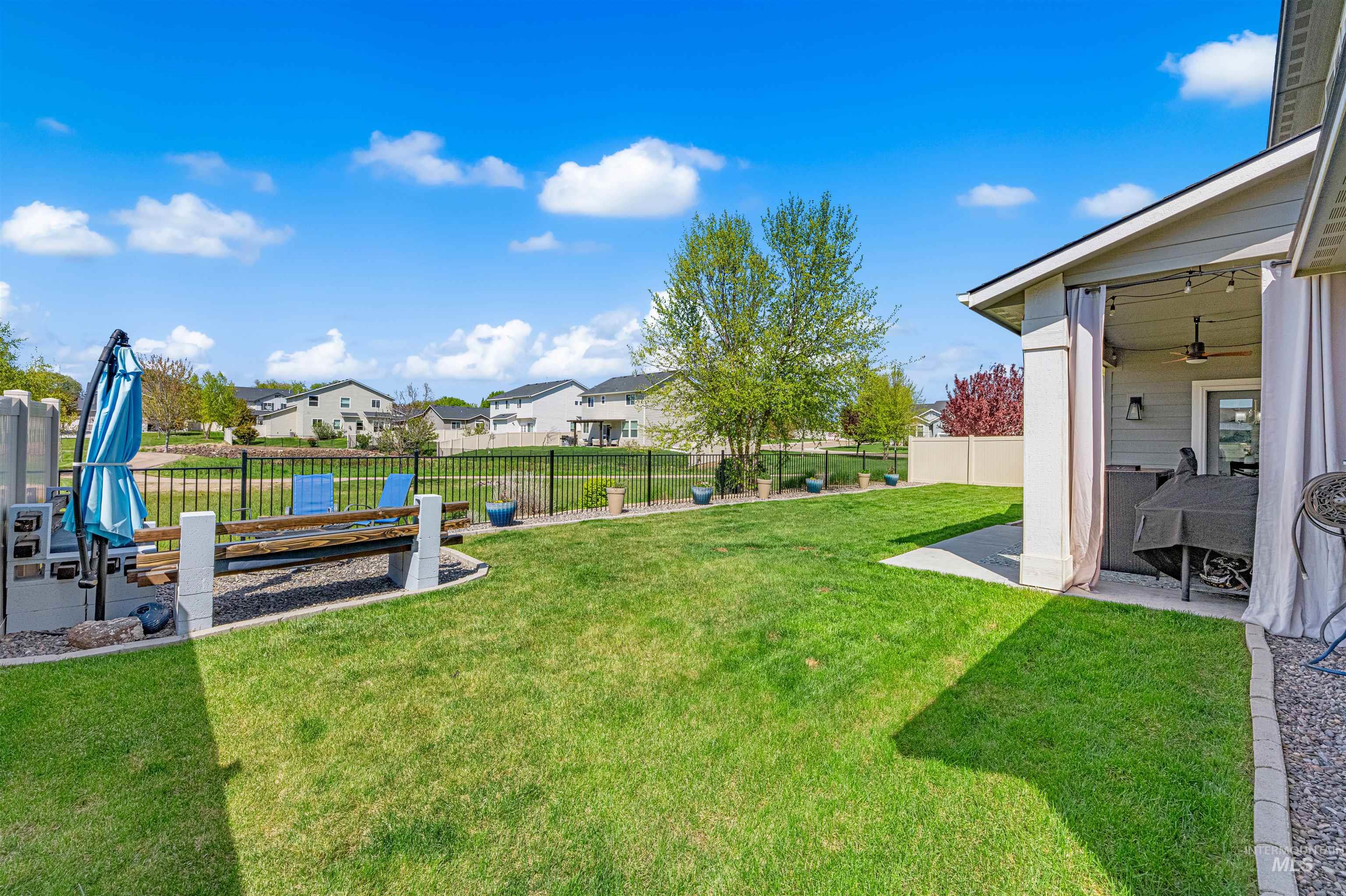 10890 West Sharpthorn Street Boise, ID 83709 - Photo 44 of 50 Expansive green lawn with a covered patio featuring a ceiling fan and string lights