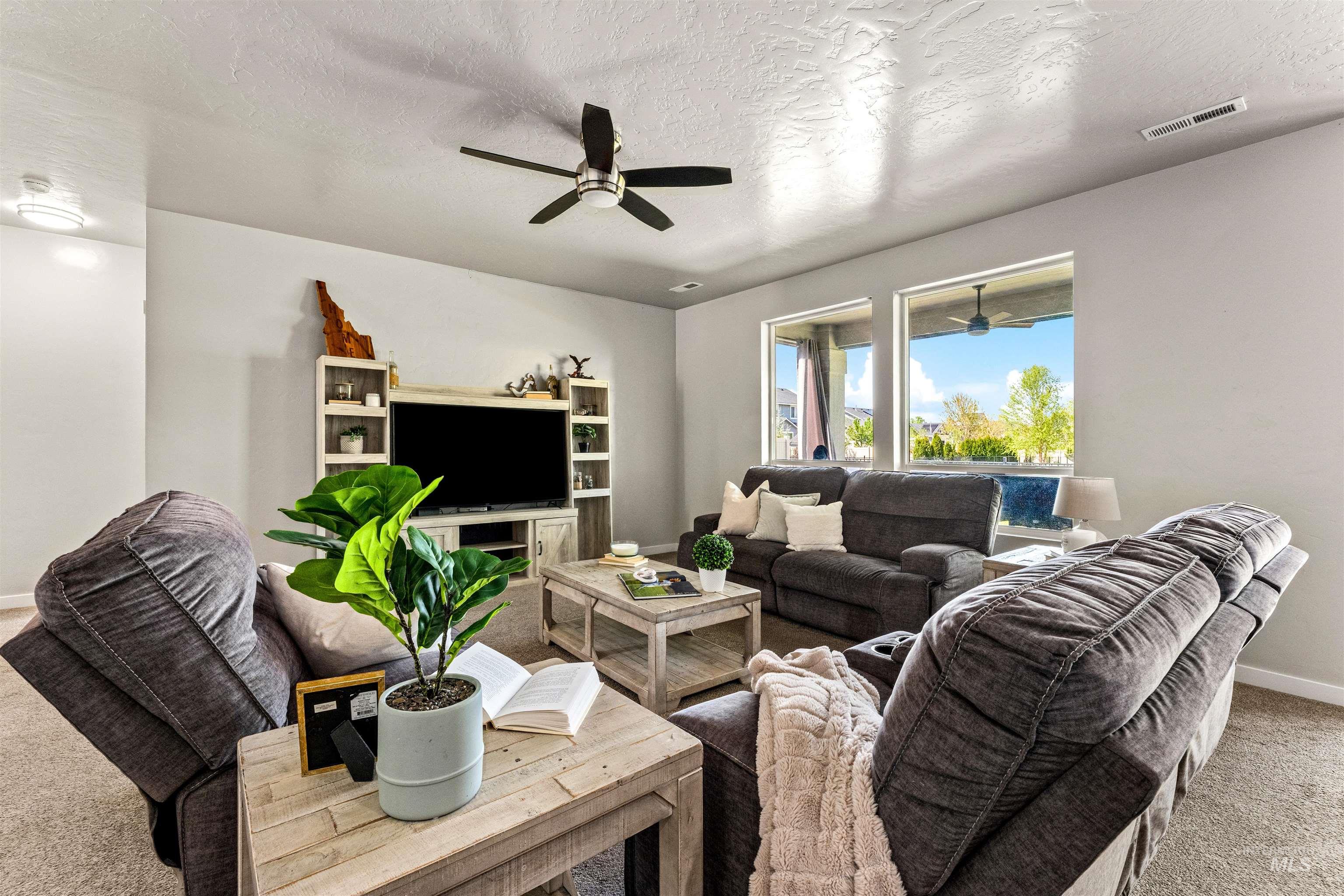 10890 West Sharpthorn Street Boise, ID 83709 - Photo 9 of 50 Living room featuring light gray walls, textured ceiling, ceiling fan with integrated lighting, and multiple windows