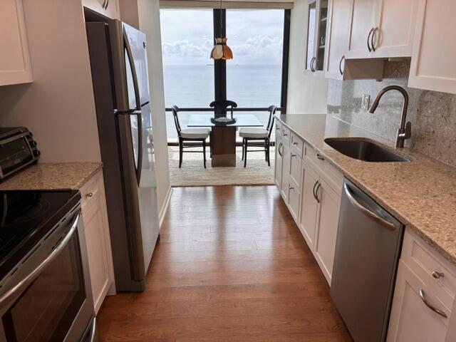 250 South Ocean Boulevard, Unit 3H Boca Raton, FL 33432 - Photo 2 of 45 a kitchen with stainless steel appliances granite countertop a refrigerator a stove and a sink with wooden floor