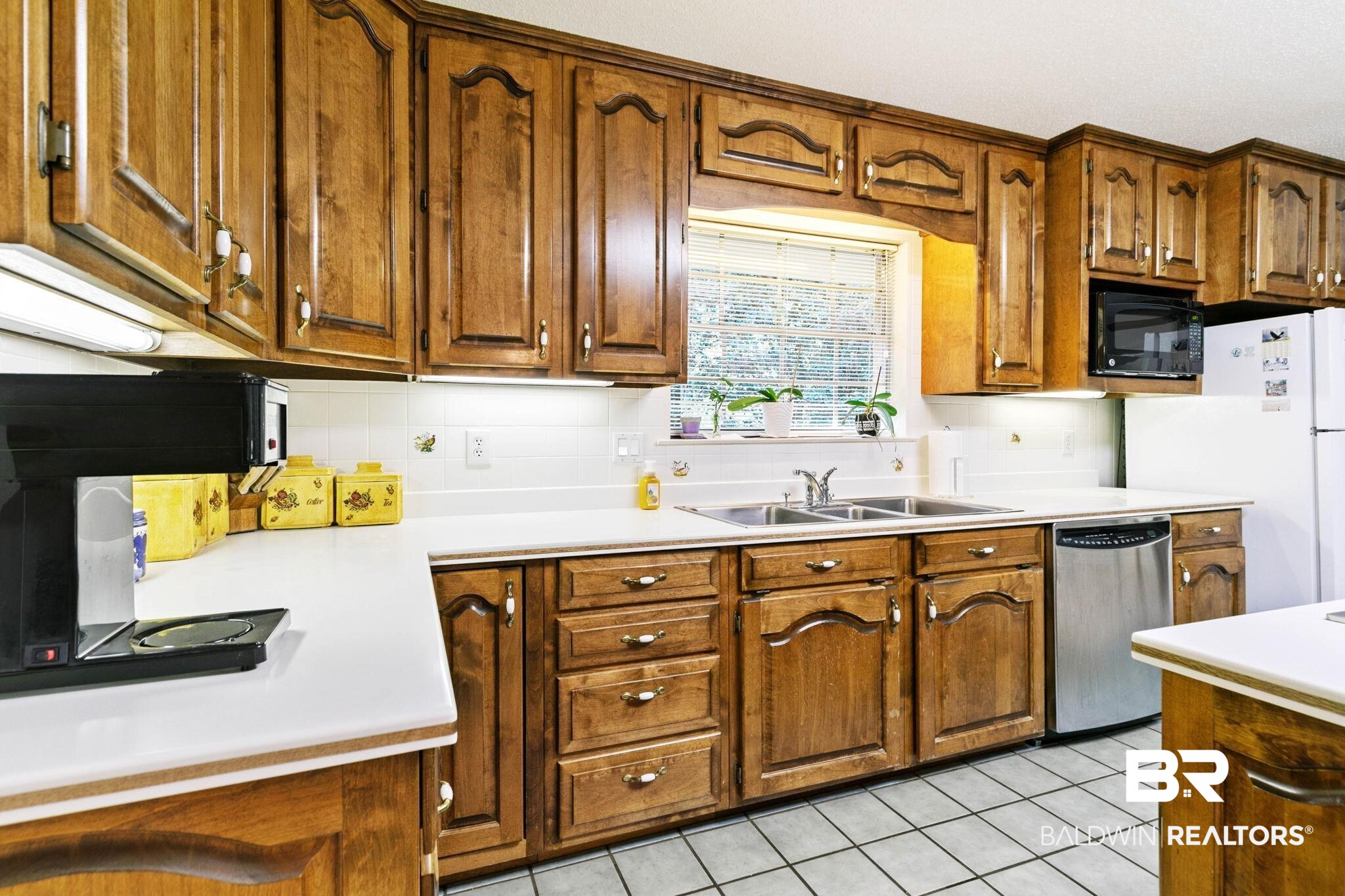 752 Evergreen Street Fairhope, AL 36532 - Photo 9 of 100 Kitchen with light countertops, light tile patterned floors, stainless steel dishwasher, brown cabinets, and black microwave