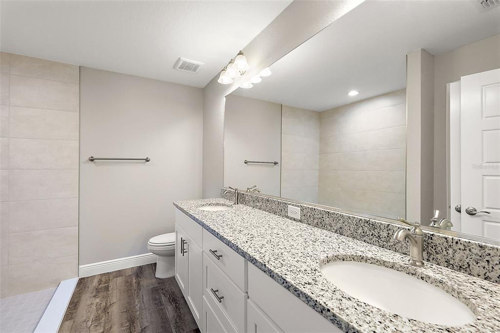 13740 Southwest 89th Street Dunnellon, FL 34432 - Photo 13 of 25 a bathroom with a granite countertop double vanity sink a mirror and a toilet