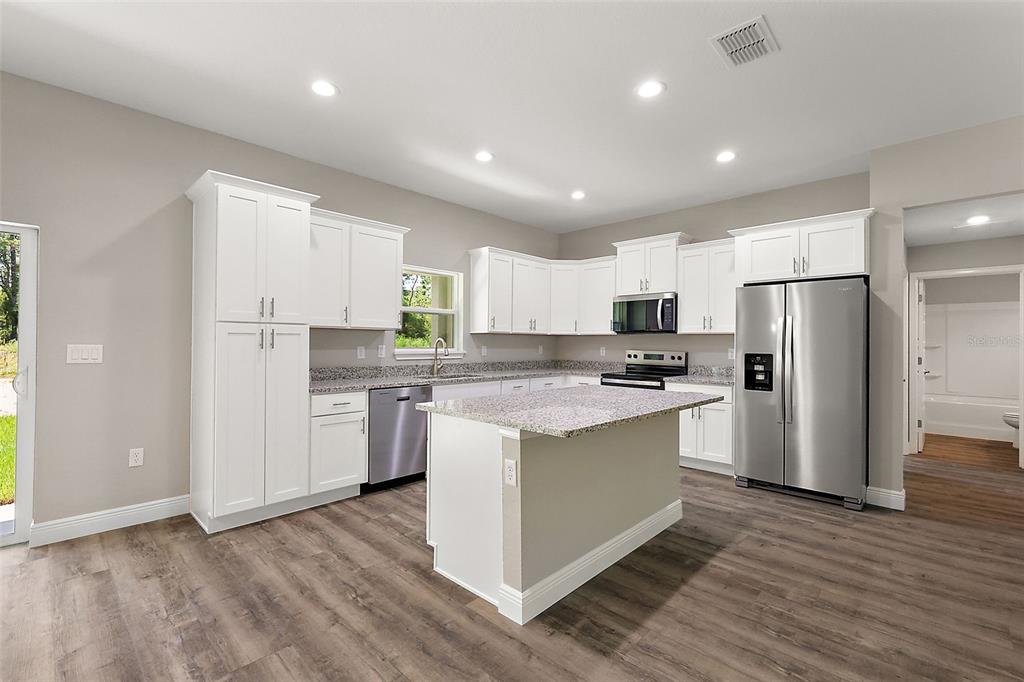 13740 Southwest 89th Street Dunnellon, FL 34432 - Photo 6 of 25 a kitchen with stainless steel appliances granite countertop a refrigerator and a stove top oven