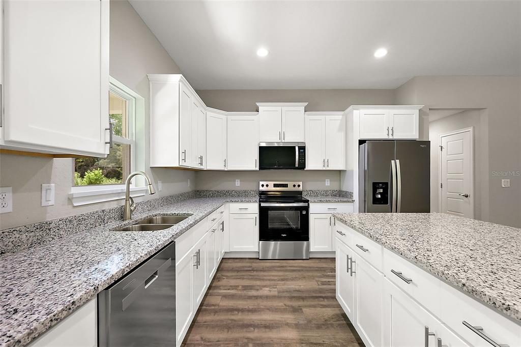 13740 Southwest 89th Street Dunnellon, FL 34432 - Photo 8 of 25 a large kitchen with kitchen island granite countertop a sink dishwasher stove and refrigerator with wooden floor