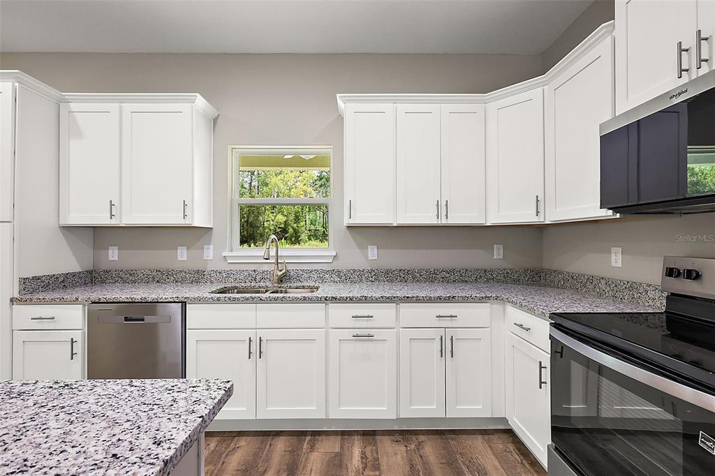 13740 Southwest 89th Street Dunnellon, FL 34432 - Photo 9 of 25 a kitchen with stainless steel appliances granite countertop a sink and cabinets with wooden floor