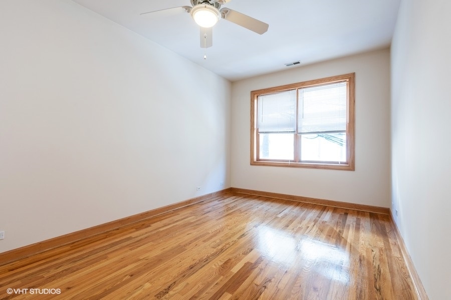 Undisclosed Address Chicago, IL 60657 - Photo 11 of 13 an empty room with wooden floor chandelier fan and windows