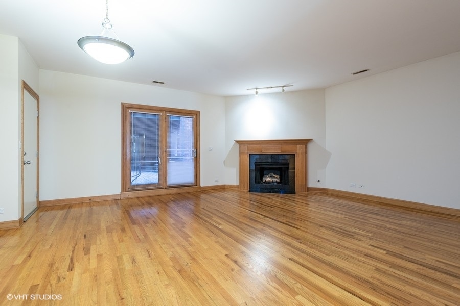 Undisclosed Address Chicago, IL 60657 - Photo 9 of 13 a view of an empty room with wooden floor fireplace and a window