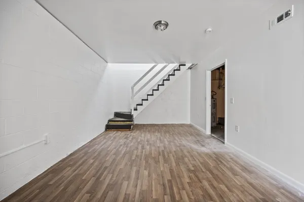 a view of an empty room with wooden floor and stairs