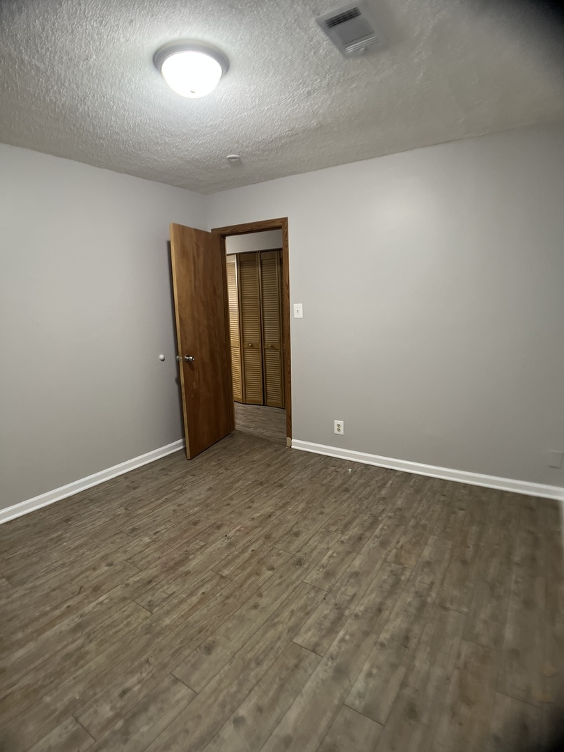 16237 Trumbull Avenue Markham, IL 60428 - Photo 14 of 18 an empty room with wooden floor and windows