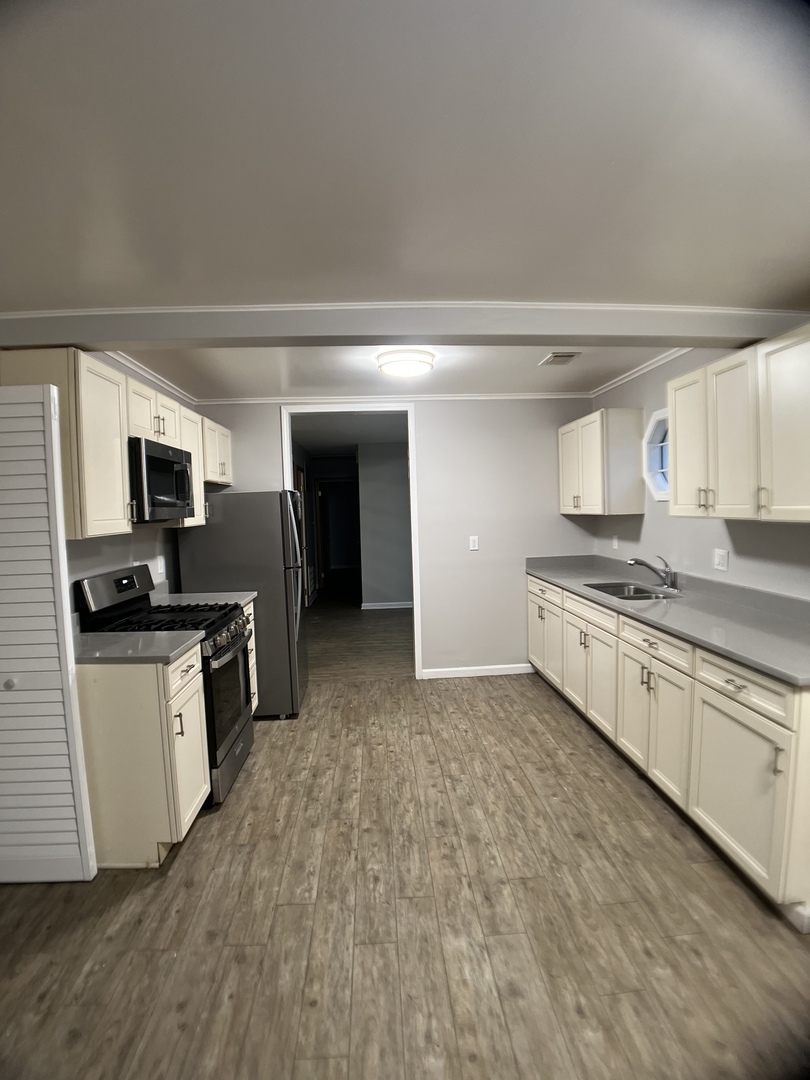 16237 Trumbull Avenue Markham, IL 60428 - Photo 7 of 18 a large kitchen with stainless steel appliances granite countertop a stove top oven a sink dishwasher and a refrigerator with wooden floor