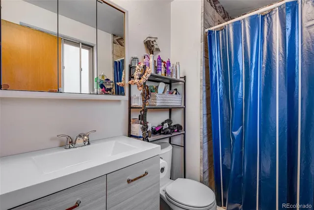 a bathroom with a sink a toilet and a shower curtain