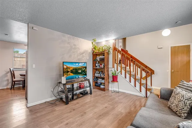 a living room with furniture and stairs with wooden floor