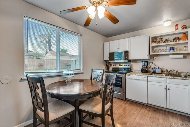 a kitchen with stainless steel appliances granite countertop a stove a sink dishwasher a dining table and chairs with wooden floor