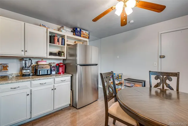 a kitchen with stainless steel appliances granite countertop a refrigerator a stove and white cabinets with wooden floor