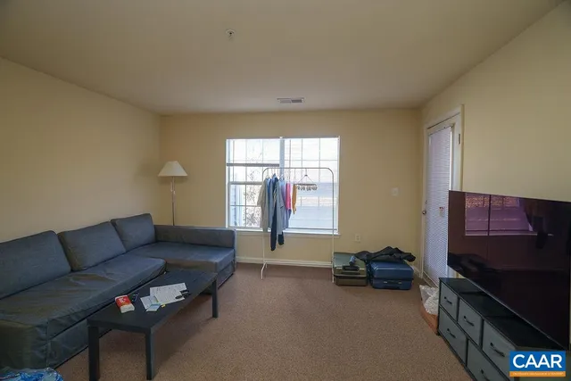 a living room with furniture a flat screen tv and a window