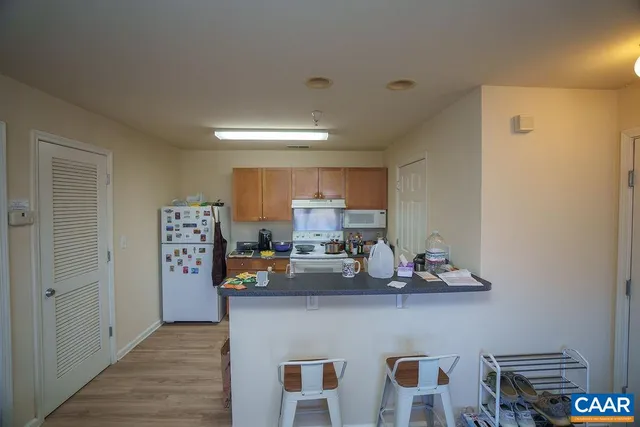 a view of dining room with kitchen island stainless steel appliances a sink and wooden floor