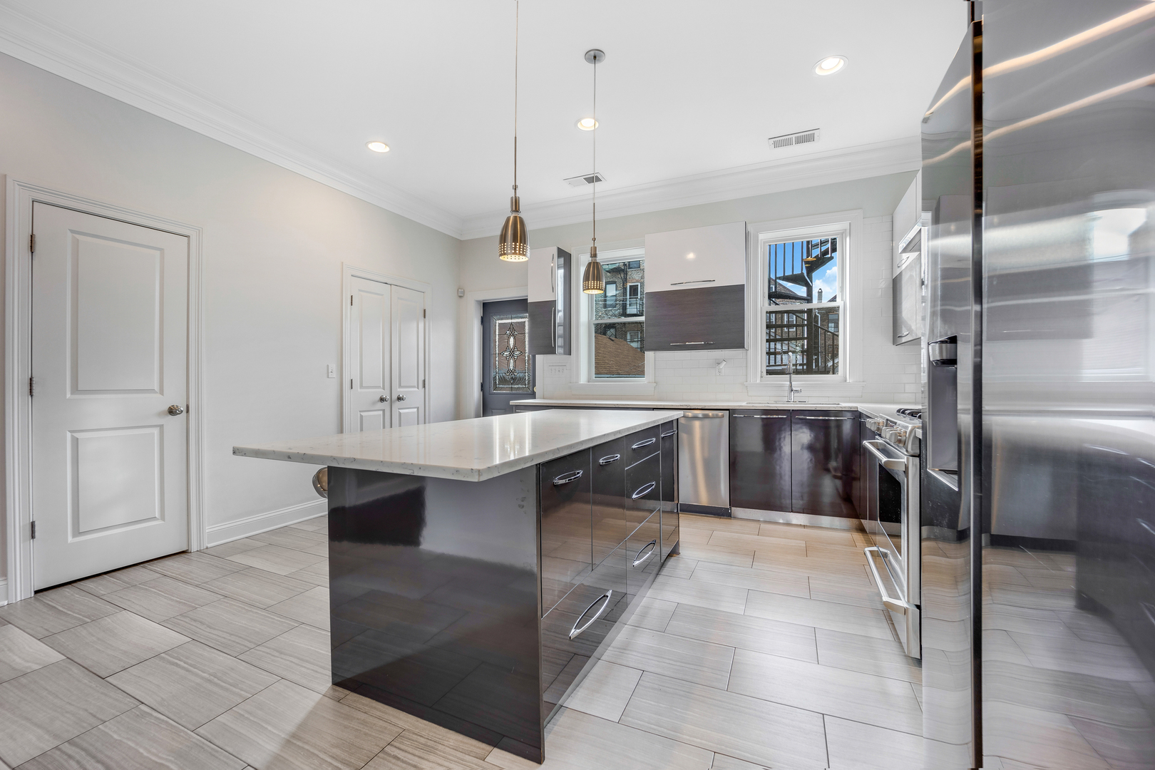 1317 West 18th Place, Unit 1F Chicago, IL 60608 - Photo 7 of 26 a large kitchen with kitchen island a sink stainless steel appliances and cabinets