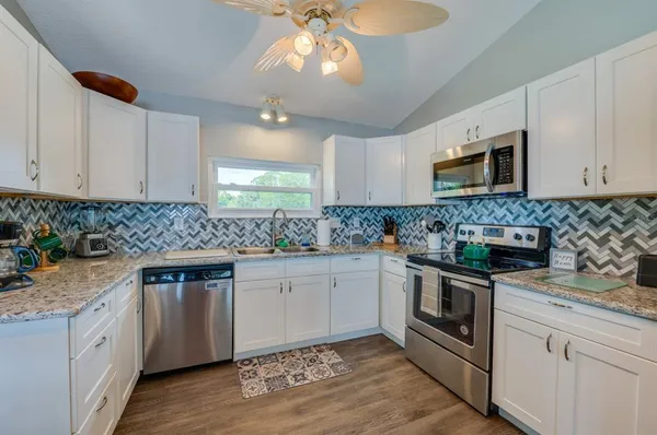 a kitchen with granite countertop a sink stainless steel appliances and white cabinets