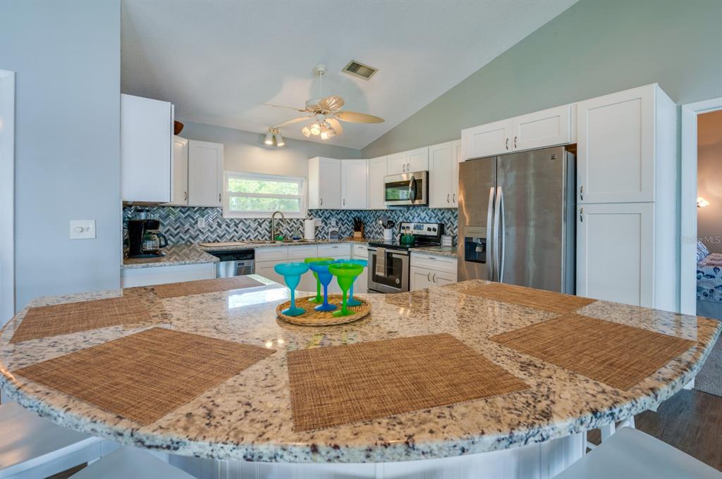 1633 Riverside Drive Daytona Beach, FL 32117 - Photo 7 of 26 a kitchen with stainless steel appliances kitchen island granite countertop a refrigerator and a sink