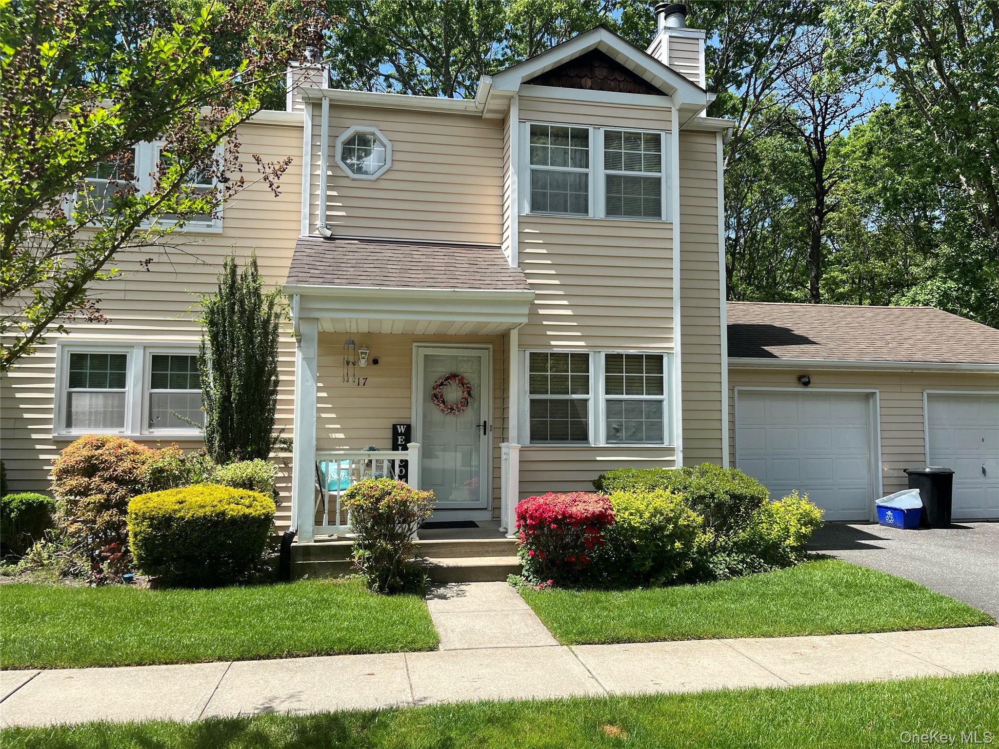 Two-story residence featuring light-colored siding, a covered front porch, and a two-car garage