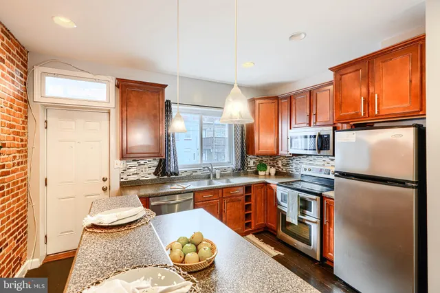 a kitchen with stainless steel appliances granite countertop a refrigerator a sink dishwasher a stove and white countertops with wooden floor