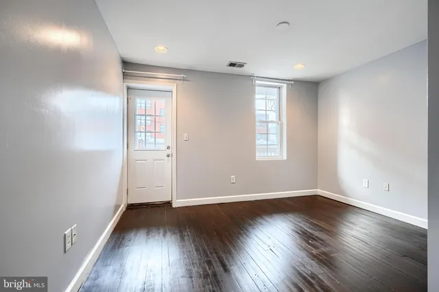 an empty room with wooden floor and windows
