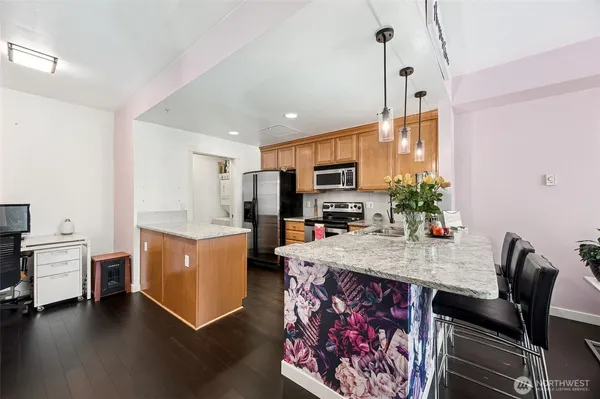 a room with stainless steel appliances kitchen island granite countertop a stove a sink a dining table and chairs