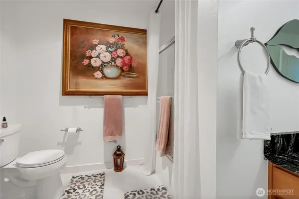 a bathroom with a toilet and a painting on the wall