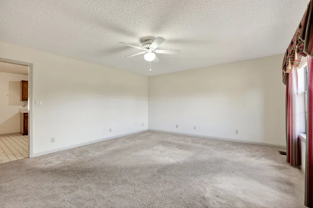 an empty room with closet and a ceiling fan