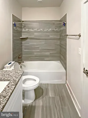 a bathroom with a granite countertop bathtub sink vanity mirror and toilet