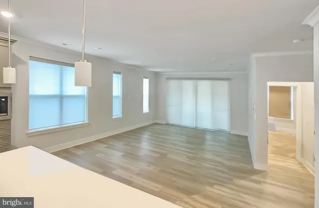 a view of an empty room with window and wooden floor
