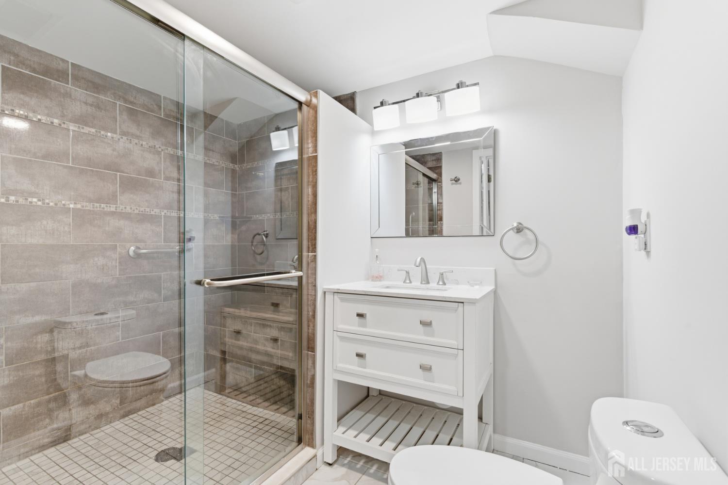 5 McKinley Street Edison, NJ 08820 - Photo 30 of 38 a bathroom with a toilet a sink and glass door