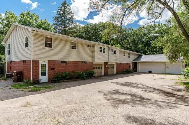 a view of a white house with a yard and large trees