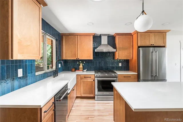 a kitchen with stainless steel appliances granite countertop a refrigerator a sink dishwasher a stove and a dining table with wooden floor