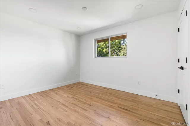 an empty room with wooden floor and window
